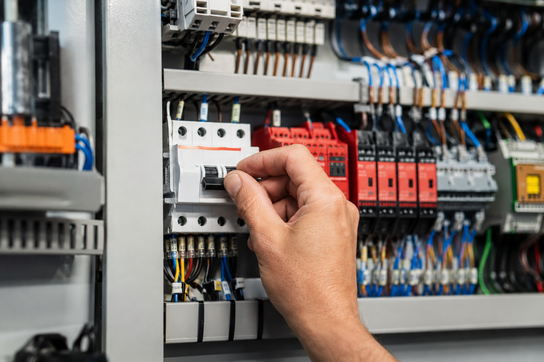 Technician operating a circuit breaker inside a modern industrial automation control panel.